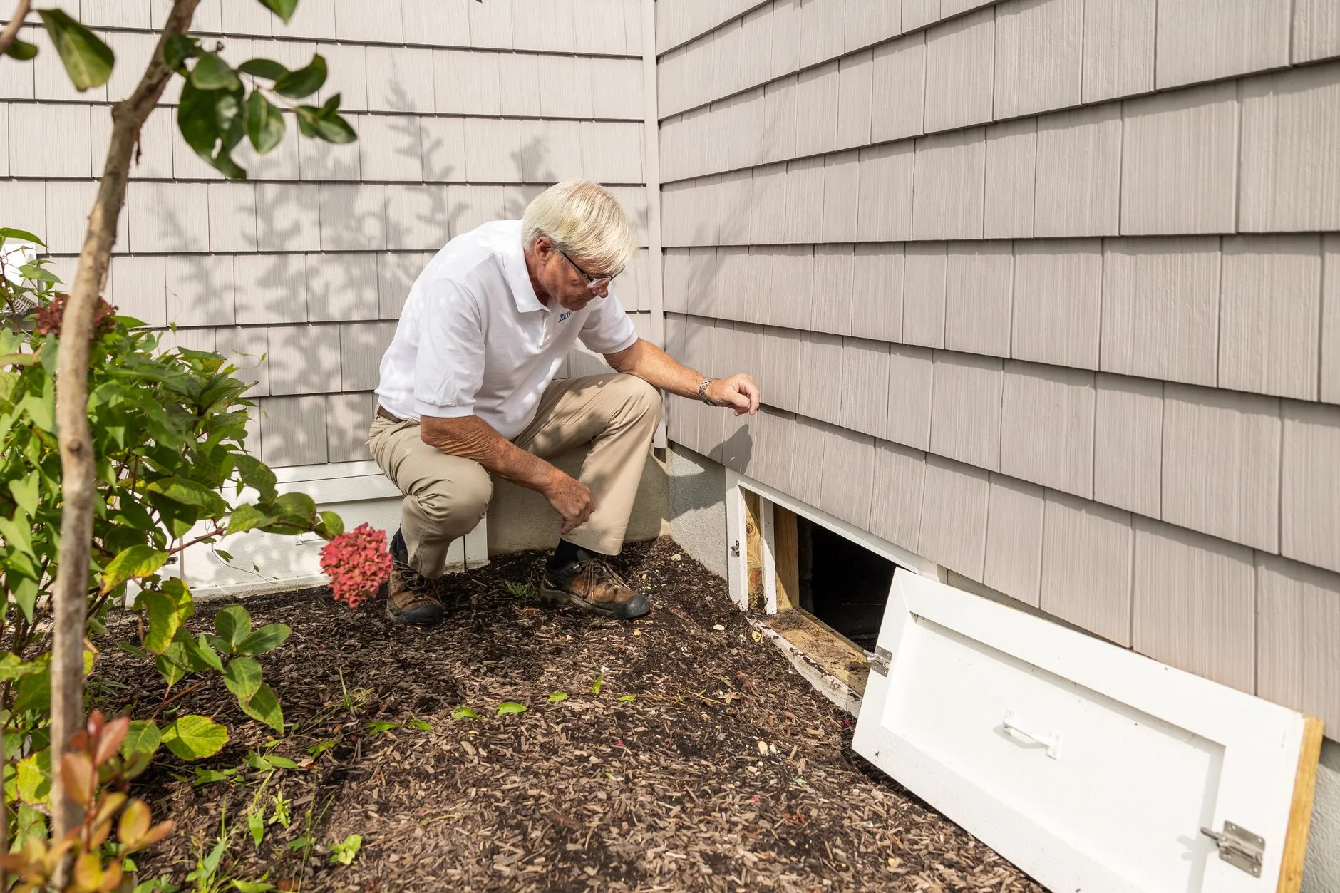 Pest control inspector examining crawl space beneath Kent WA home for pest evidence